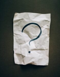 Crumbled up paper with a hand-written question mark