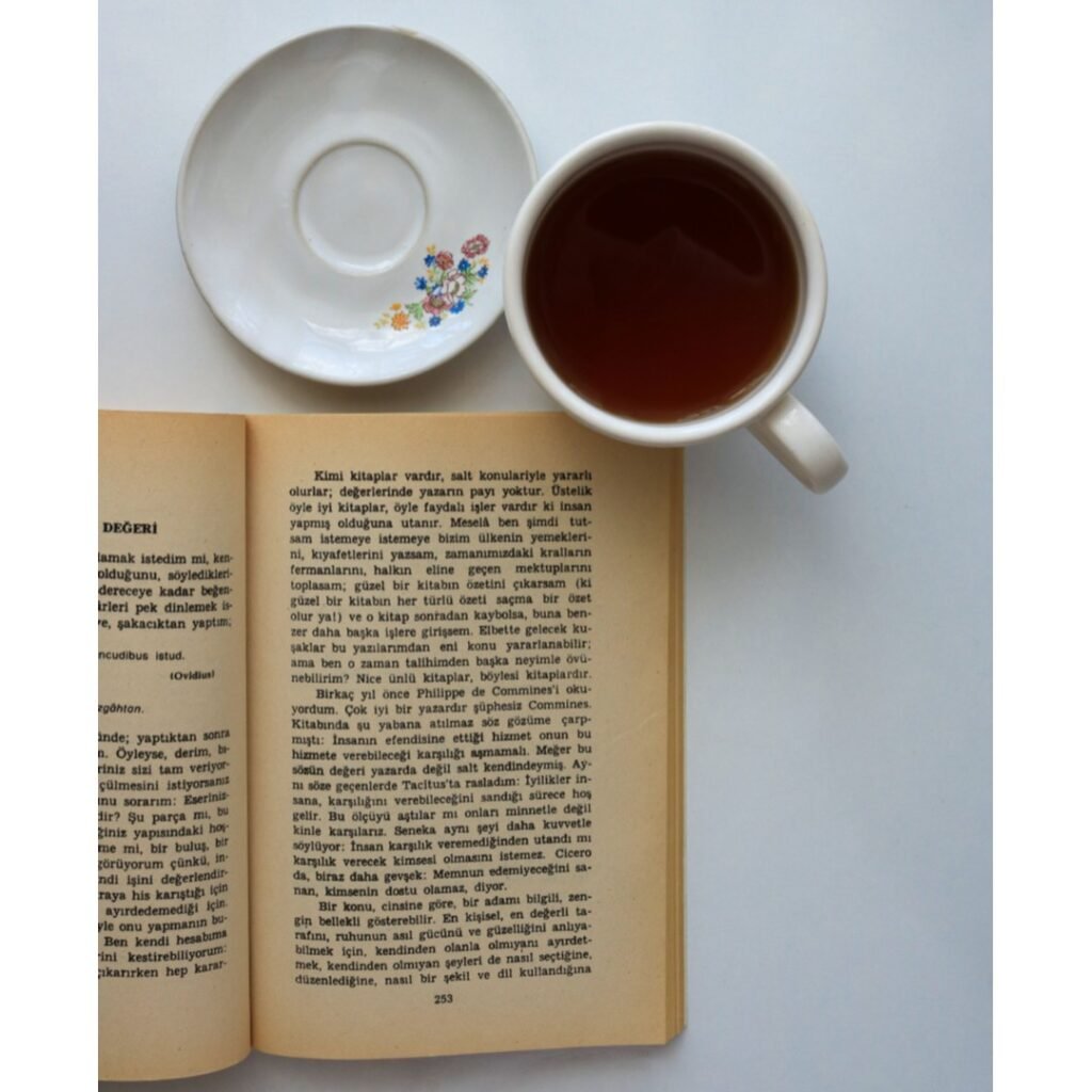 Cup of tea and a saucer arranged by a book