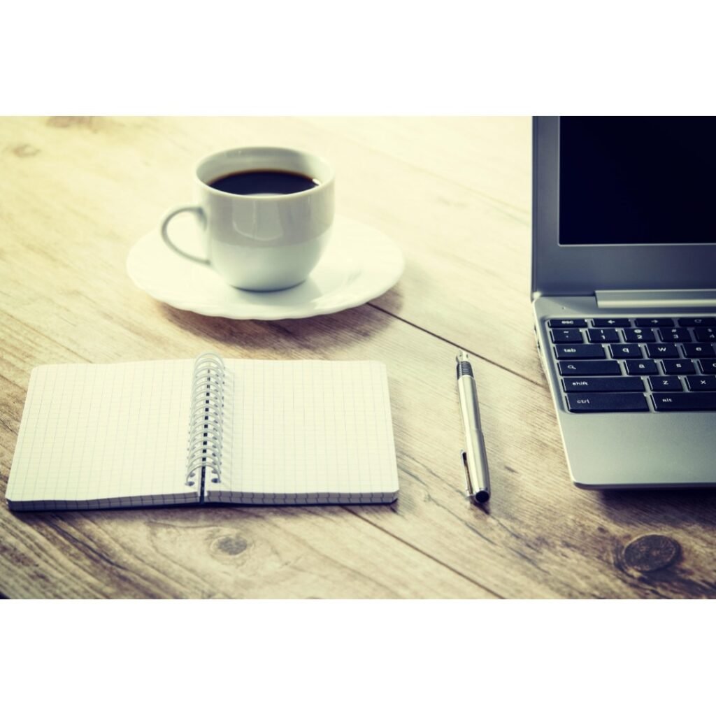 Notebook, pen, laptop, and coffee on a desk — a calm workspace for organizing call notes.
